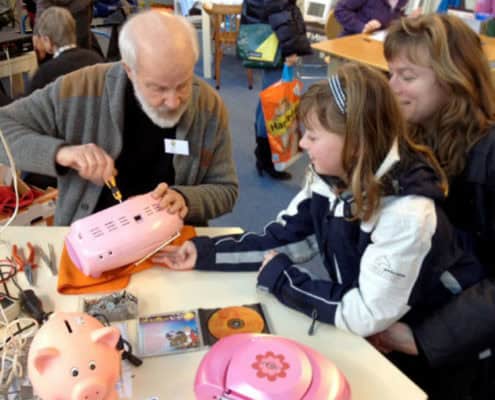 Oudere heer repareert speelgoed van meisje